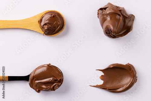 Image of spoons with chocolate cream on white background
