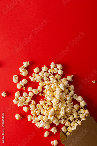 Vertical image of pop corn lying on red surface
