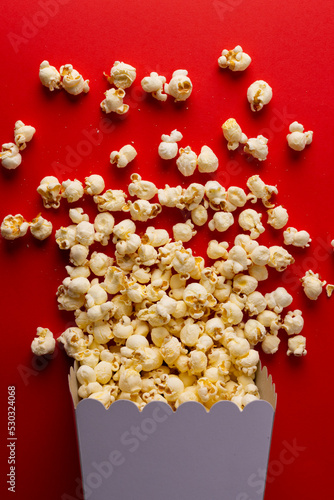 Vertical image of pop corn lying on red surface