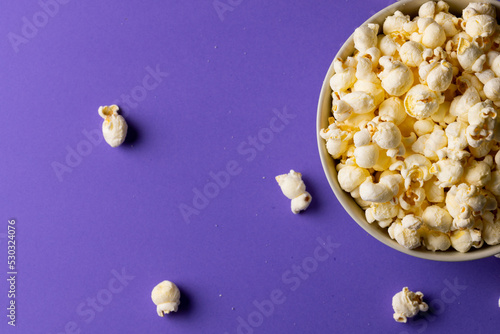 Image of pop corn in bowl lying on violet background