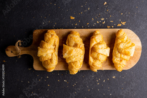 Image of croissants lying on wooden board on dark grey surface