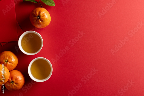 Composition of traditional chinese decorations and oranges on red background
