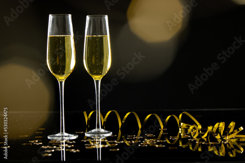 Composition of close up of new years champagne with confetti on black background