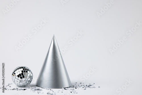 Composition of close up of new years hat and confetti on white background