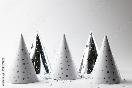 Composition of close up of new years hats and confetti on white background