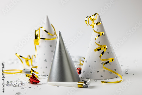 Composition of close up of new years hats and confetti on white background