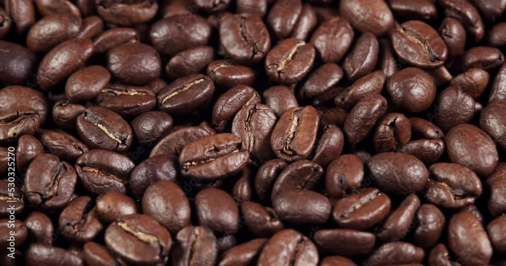 Roasted coffee beans dolly shot. Aromatic coffee beans move slowly. Slide slow motion close-up of whole roasted coffee beans. Roasted coffee beans dolly shot. Aromatic coffee beans move slowly. Slide slow motion close-up of whole roasted coffee beans.