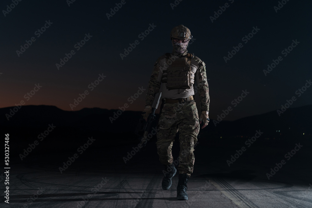 Army soldier in Combat Uniforms with an assault rifle, plate carrier and combat helmet going on a dangerous mission on a rainy night. Army soldier in Combat Uniforms with an assault rifle, plate carrier and combat helmet going on a dangerous mission on a rainy night.