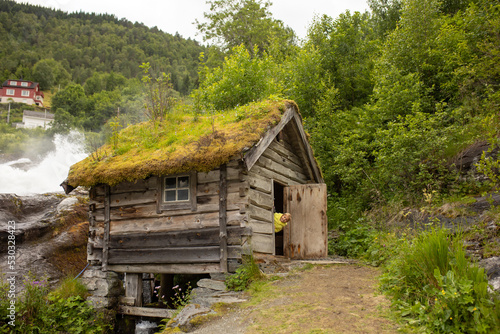 Amazing little wooden small house next to a waterfall on the dock of Hellesylt, child playing in the house photo