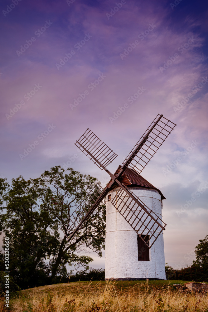 Old windmill against a wispy sky, with purple tones