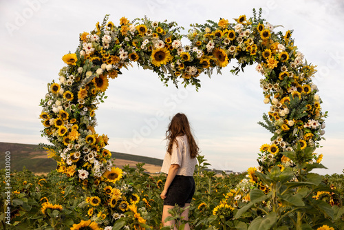 girl standing in sunflower heart arch