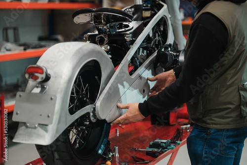 Repairman repair motorcycle, maintenance in garage. Mechanic fixing bike in a modern shop