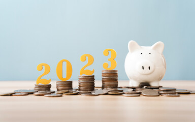 Gold wooden number year 2023 on top stack of coins with sky blue background and copy space. saving money and financial plan concept for investment in new year 2023.
