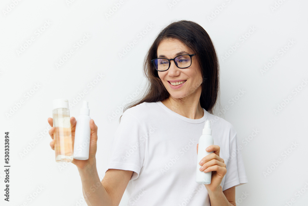 horizontal photo on a light background of an adult, beautiful woman with long hair, standing with self-care products in her hands and smiling pleasantly at the camera with a wide smile horizontal photo on a light background of an adult, beautiful woman with long hair, standing with self-care products in her hands and smiling pleasantly at the camera with a wide smile