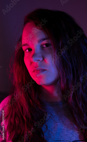 portrait of a girl with a colored light. Pink and blue color on the face of a curly-haired girl