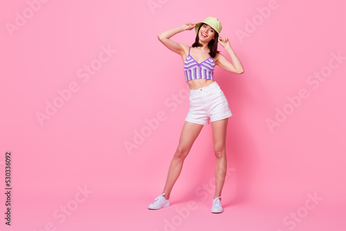 Full size photo of pretty lovely lady arms touch panama hat posing empty space isolated on pink color background