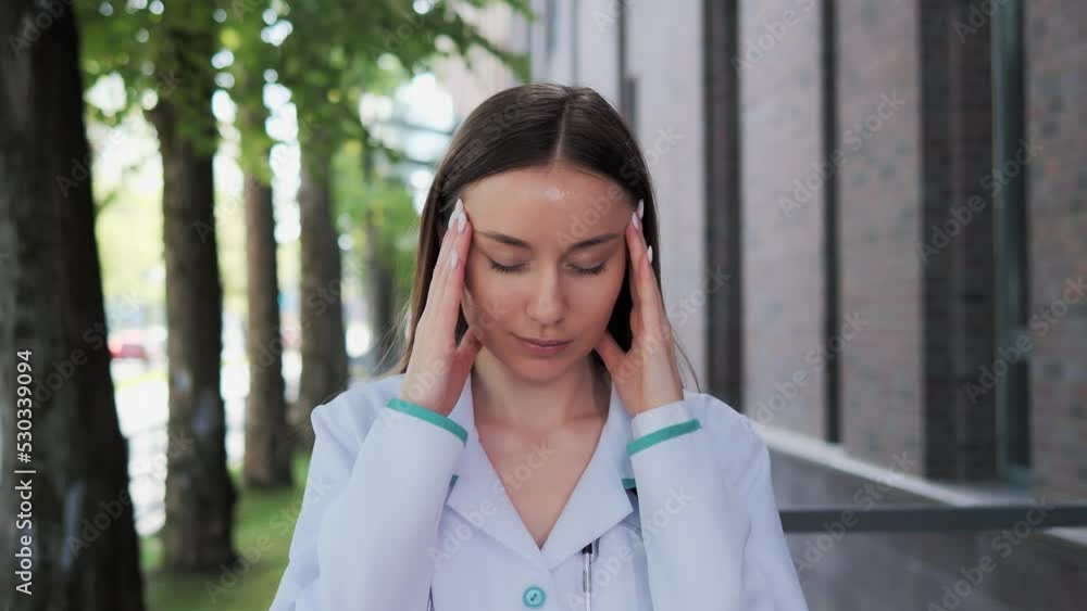 Stressed exhausted professional doctor having headache outdoor, hard day, feel eye strain fatigued from a large amount of work. Tired overloaded physician suffer from headache pain near hospital. Stressed exhausted professional doctor having headache outdoor, hard day, feel eye strain fatigued from a large amount of work. Tired overloaded physician suffer from headache pain near hospital.