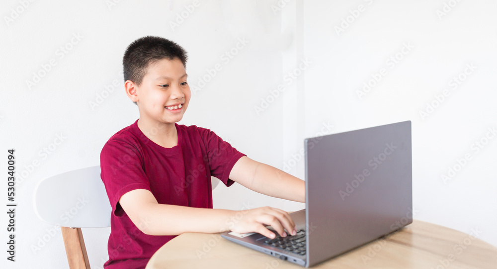 Asian boy studying online on computer laptop with smiling and happy face at home. online education and e-learning concept. Asian boy studying online on computer laptop with smiling and happy face at home. online education and e-learning concept.