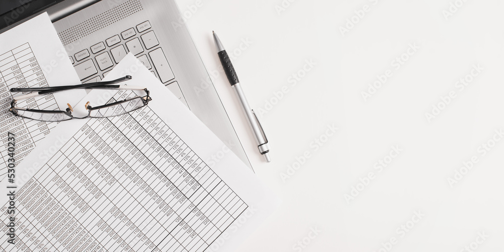 Accounting, business and finance banner with copy space. Top view documents, bills, pen, laptop and eyeglasses on a white desktop Accounting, business and finance banner with copy space. Top view documents, bills, pen, laptop and eyeglasses on a white desktop