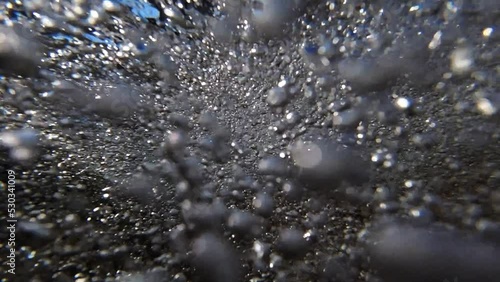 Under water Super slow motion of tide going back out to sea. Crystal clear water. Millions of bubbles rushing passed the camera with amazing fluid motion
