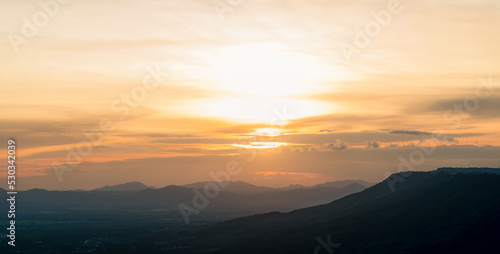 Landscape of mountain range with sunset sky. Mountain at dusk. Orange sky and clouds at sunset. Mountain valley. Mountain layer at dusk. Beauty in nature. Tranquility scene. Beautiful sunset sky.