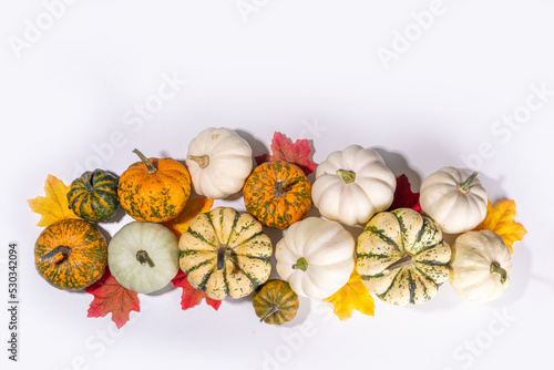 Autumn decorative pumpkins with fall leaves on white table background. Fall Thanksgiving halloween holiday greeting card background, harvest concept. Top view, copy space