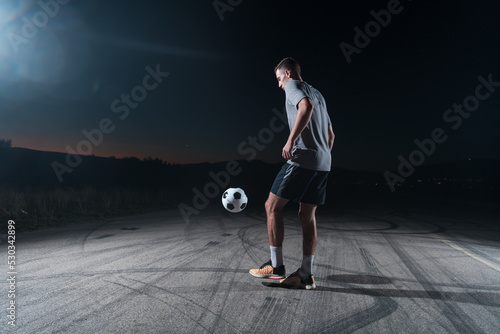 portrait of a young handsome soccer player man on a street playing with a football ball. © .shock
