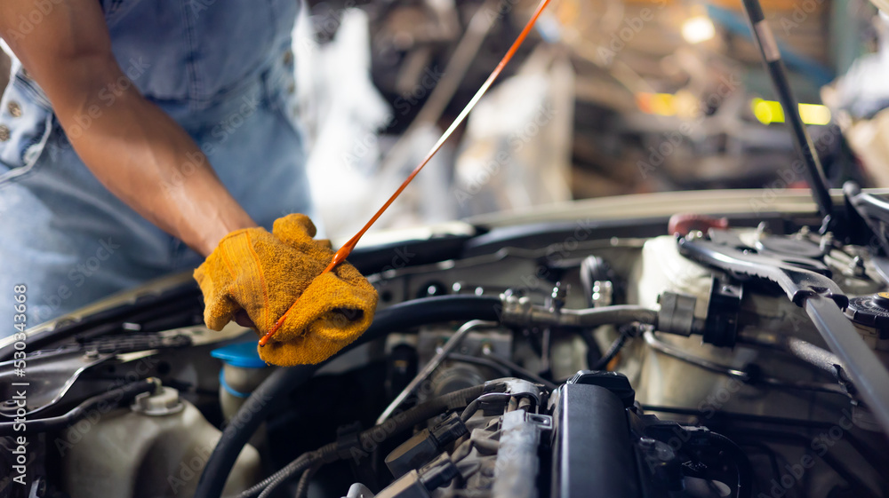 Closeup hand and spanner. Auto car mechanic checking the oil level of the car engine. Closeup hand and spanner. Auto car mechanic checking the oil level of the car engine.