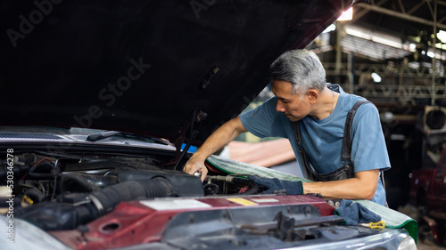 senior asian male mechanic engineering working on Vehicle in Car Service. Repair specialist, technical maintenance. Small business owner.