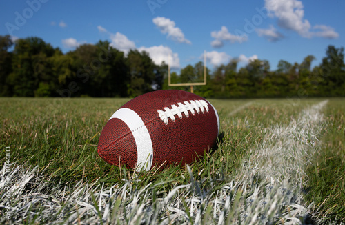 Football on field with goalposts on background 