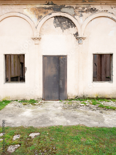 Old abandoned building with an iron door and broken windows. Front view. © jockermax3d