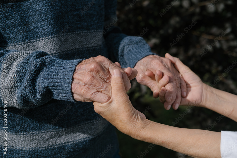 Hands holding together elderly man and woman, couple, husband and wife. Love and care consept