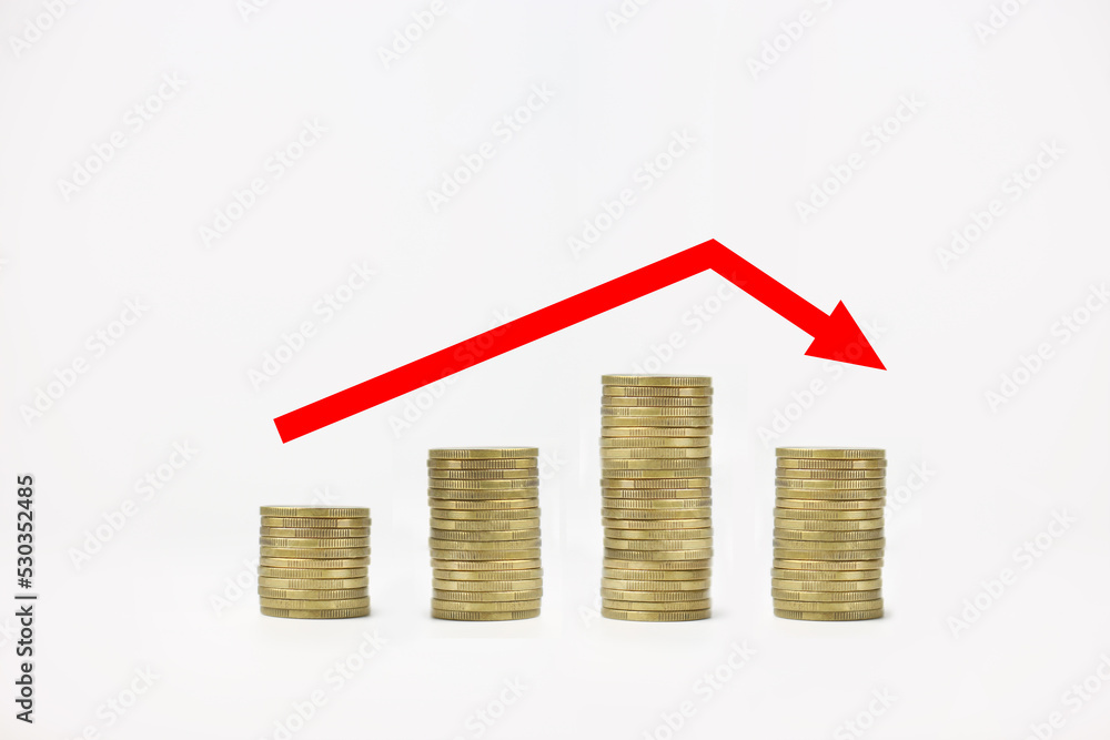 Stacked coins on a white isolated background with a red arrow. Investment growth and fall concept Stacked coins on a white isolated background with a red arrow. Investment growth and fall concept