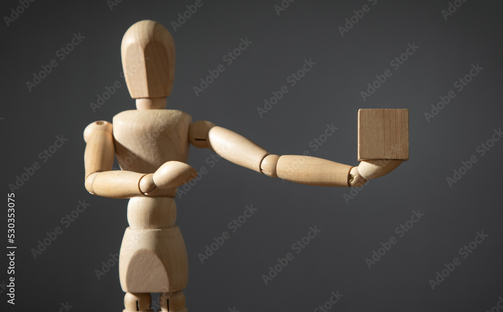 Wooden human figure holding wooden empty cube. Wooden human figure holding wooden empty cube.