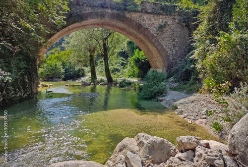 Historical stone bridge over a wild river in the Italian alps.