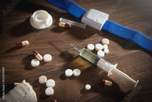 Pills and syringe on the wooden table.