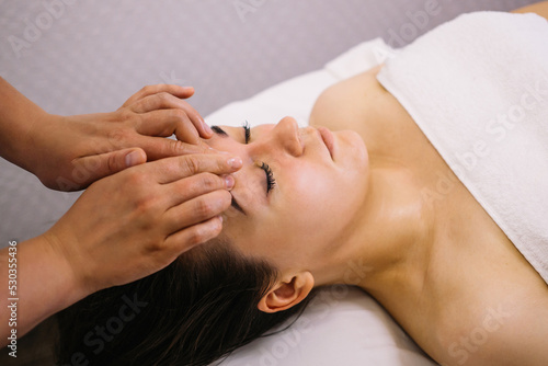 Woman receiving facial massage in beauty salon.Beauty and skincare concept with a beautiful woman. Middle aged female relaxed with massage for facial lifting 