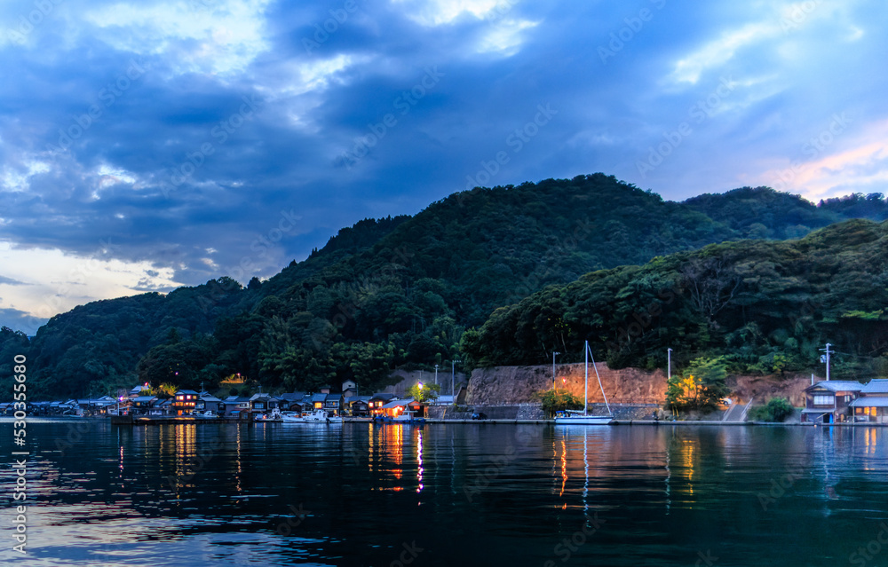 Dramatic clouds over small harbor and coastal mountains at blue hour