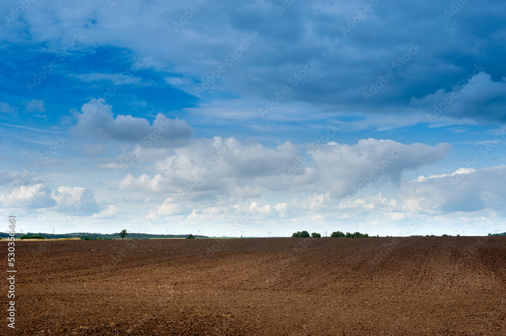 areas of arable fields, landscape, preparation for sowing for the season Agriculture, agrarian plowed areas, and beautiful blue sky with clouds