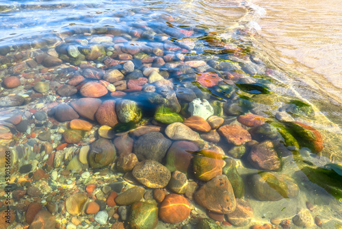 Clear sea water. Small stones at the bottom near the shore. Texture transparent clear water © Adriana