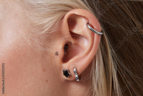 Professional placing the jewel of piercing on the temple on the head with ball. Tragus type. photo