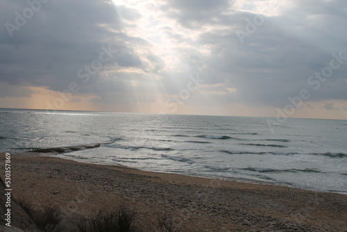 Fototapeta Naklejka Na Ścianę i Meble -  Balade sur la plage avec vue sur les rayons du soleil traversant les nuages