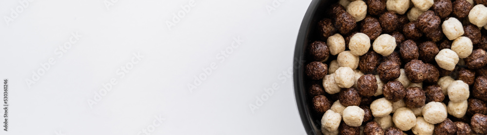 top view of cereal balls with chocolate and vanilla flavors in bowl isolated on white, banner. top view of cereal balls with chocolate and vanilla flavors in bowl isolated on white, banner.