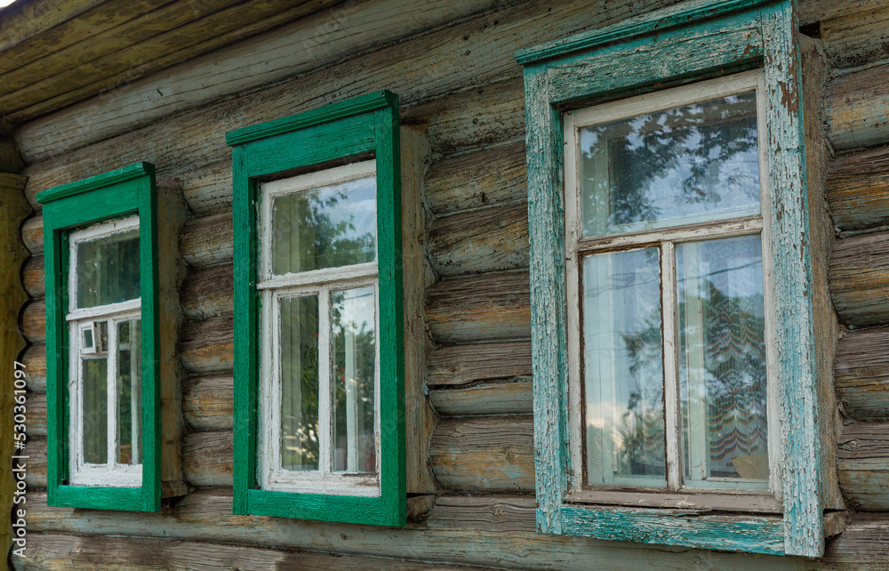 Fototapeta premium The beautiful old windows with beautifully designed platbands window on an old wooden house in the city of Tula