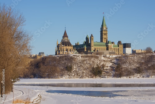Gothic revival buildings and towers of parliament hill, seen from the park along Ottawa river on a sunny witer day with clear blue sky. Ontario, Canada  photo