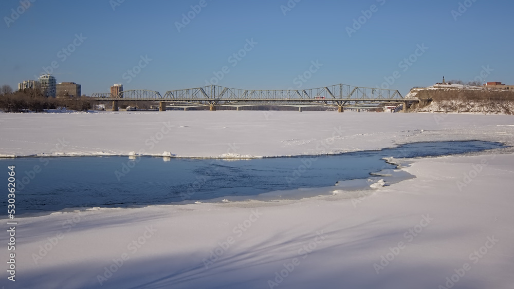 Frozen Ottawa river with Alexandra bridge ad Nepean point on a sunny winter day with clear blue sky. Ottawa, Ontario, Canada