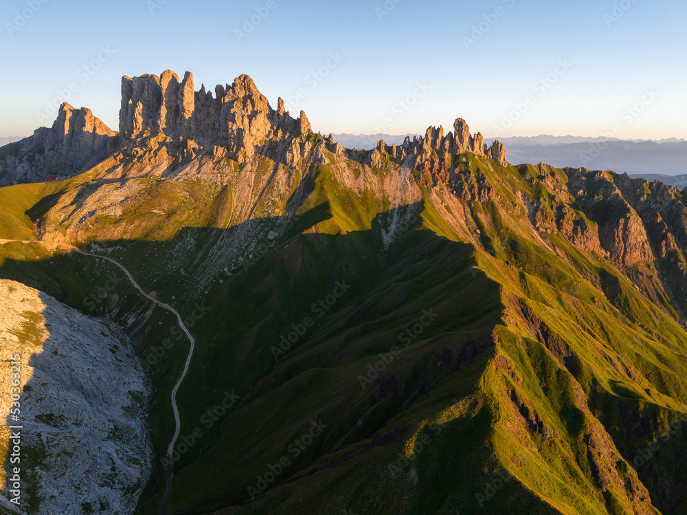 Sunrise in the Dolomites mountains with fog and mist rolling around the peaks. Hiking path leading to the hills.