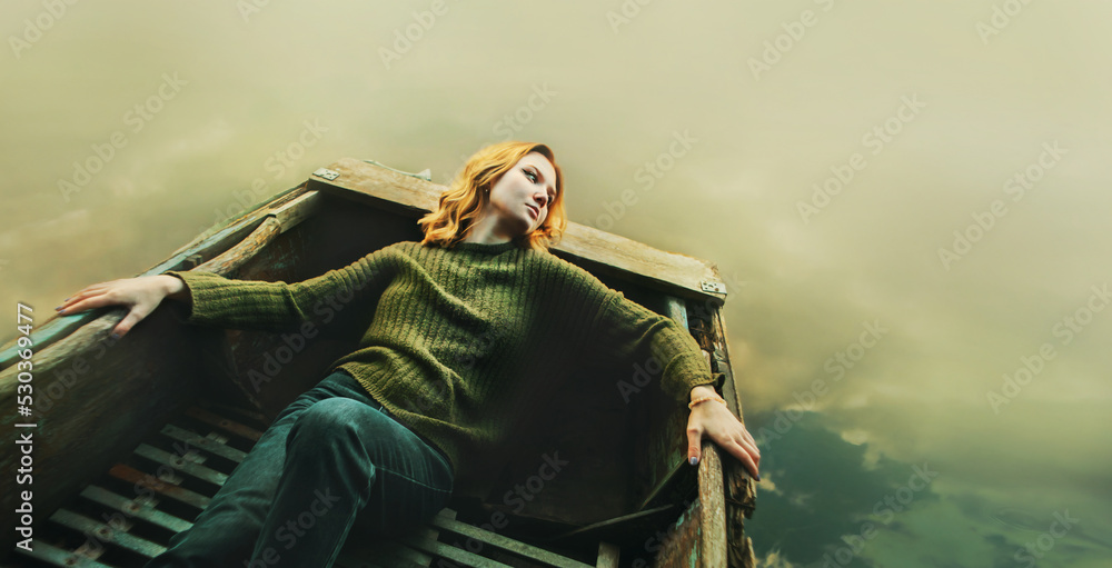 A beautiful blonde woman in a green vintage sweater and blue jeans lies  relaxed in the