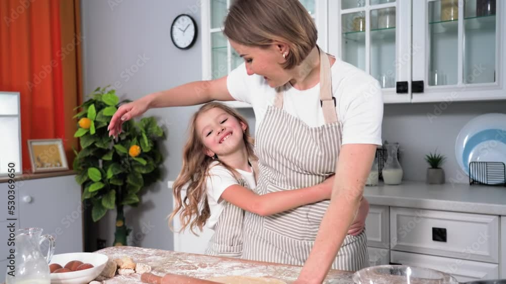cooking, joyful girl runs up to young woman and rolls out dough for cookies at table background of kitchen, relationship of daughter and mother cooking, joyful girl runs up to young woman and rolls out dough for cookies at table background of kitchen, relationship of daughter and mother
