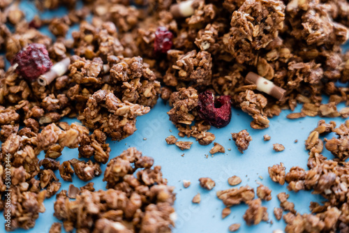 close up of crunchy granola with dry berry on blue background.